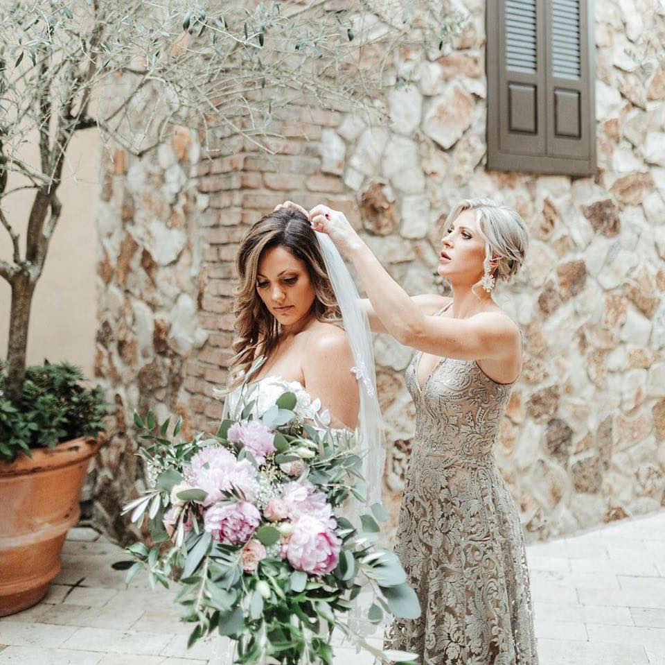Stylist adjusting bride's veil during wedding preparation